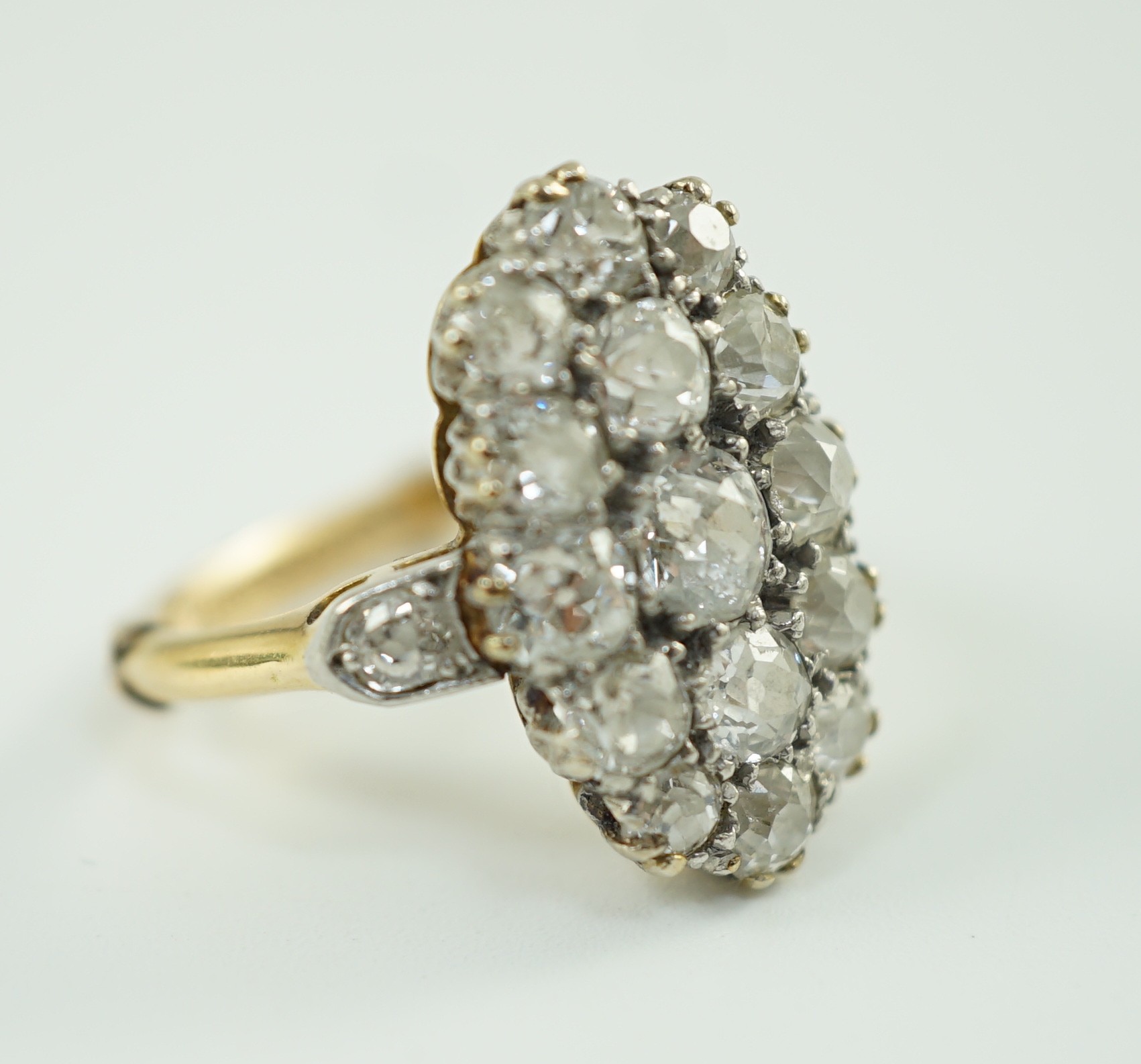 An 18ct gold and oval diamond cluster dress ring, with diamond set shoulders